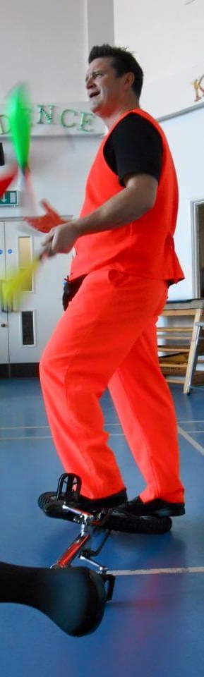 Circus skills performer balancing on a unicycle while juggling