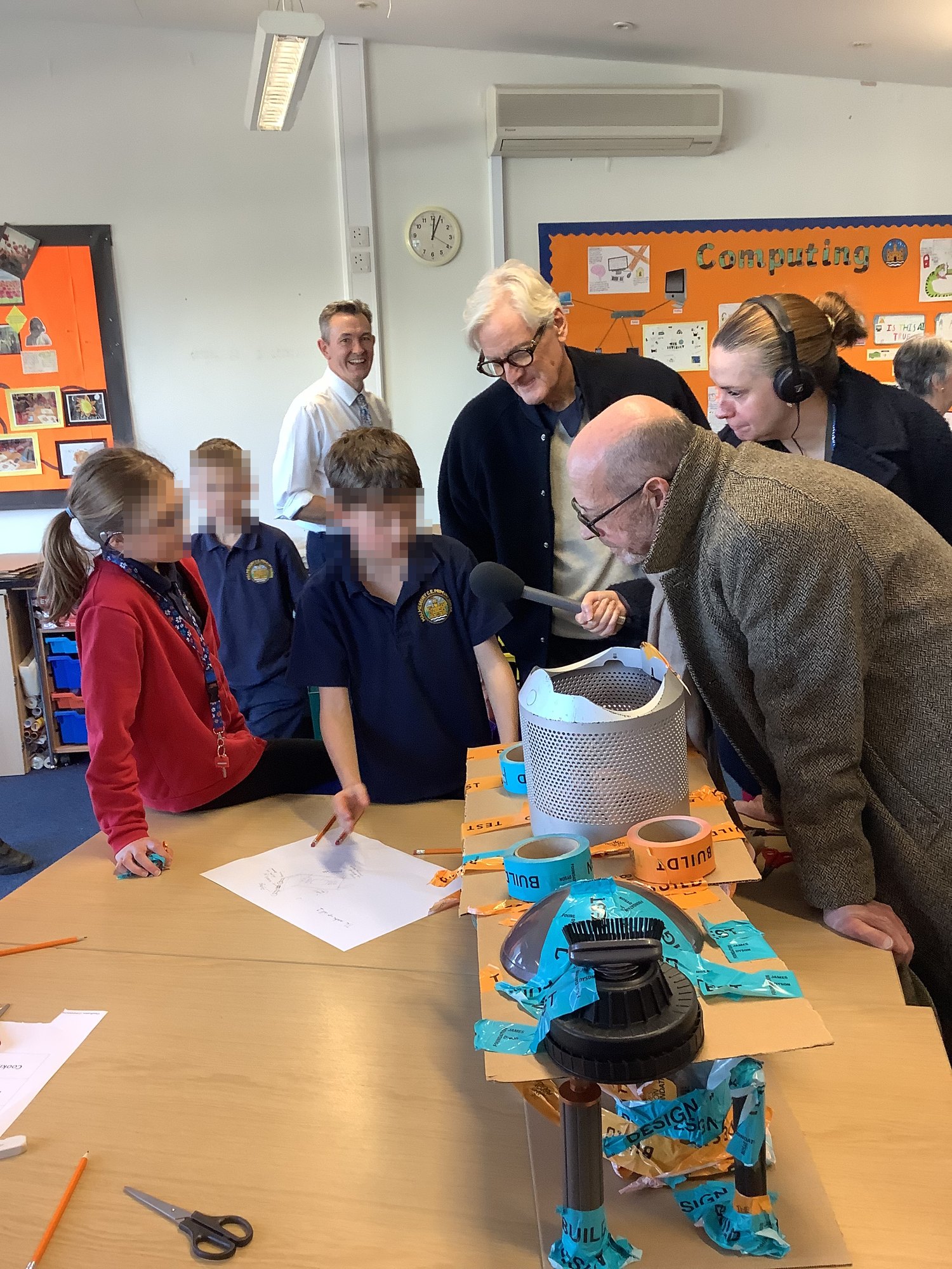 Sir James Dyson and Nick Robinson of BBC Radio 4 with pupils looking at a model built from Dyson parts