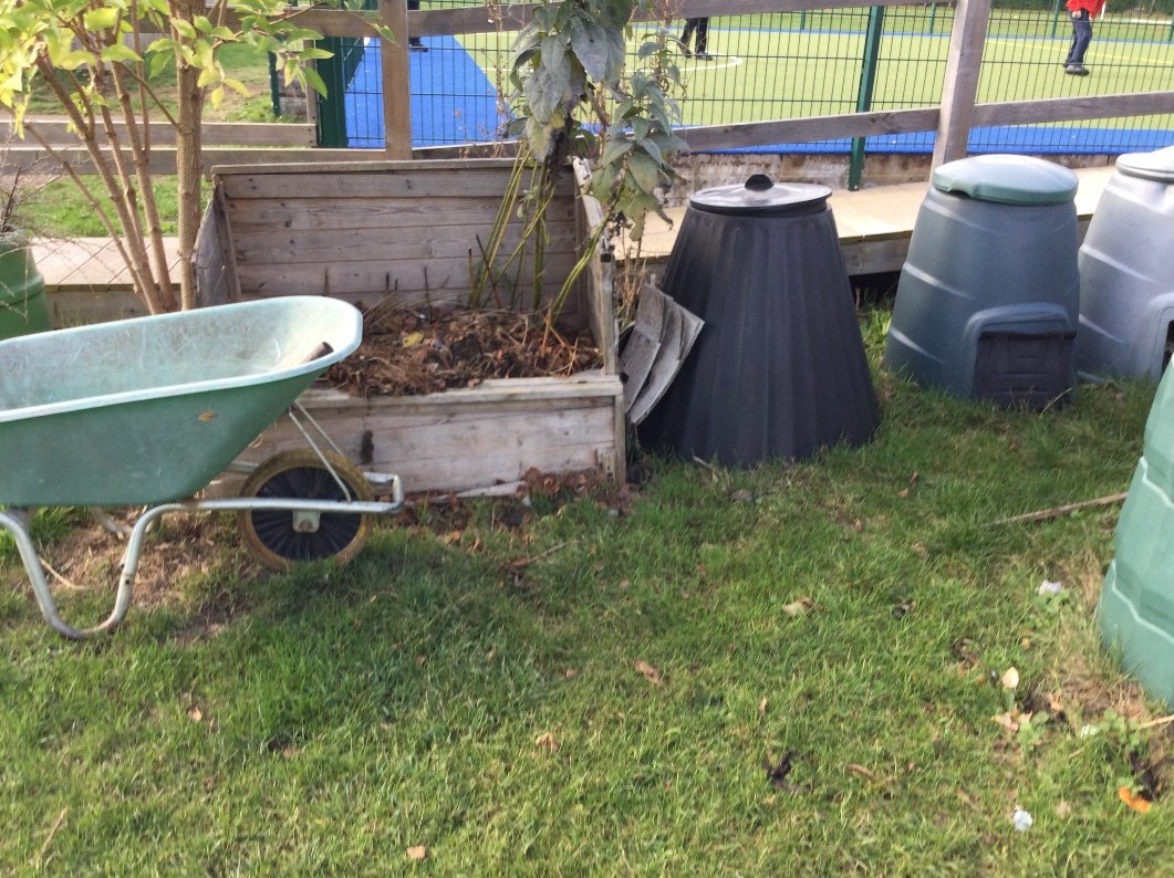 Compost bins and a wheelbarrow in the school grounds