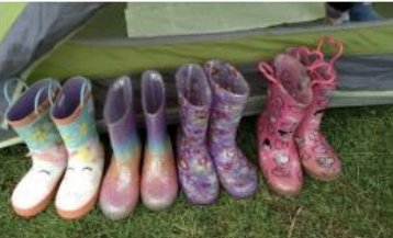 A row of wellington boots outside a tent