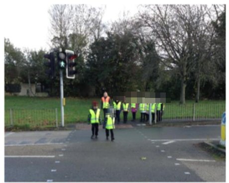 Children in high-visibility vests at a pedestrian crossing